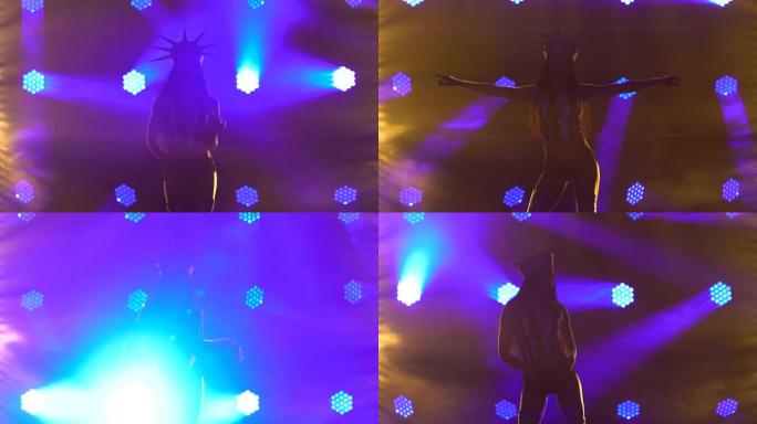 性感的黑发女郎穿着夜总会套装跳舞，美国自由女神像。深色背景和动态的蓝色霓虹灯。剪影。去参加舞蹈表演。