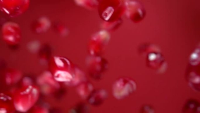 多汁的成熟石榴颗粒落在酒红色背景上