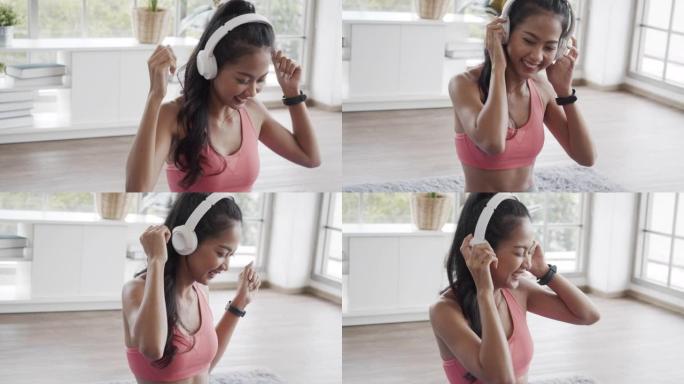 穿着运动服的美丽亚洲女性在家里的客厅里做瑜伽锻炼时听音乐。