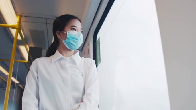在泰国冠状病毒大流行期间，亚洲女商人乘客在前往机场的火车上戴着外科口罩。