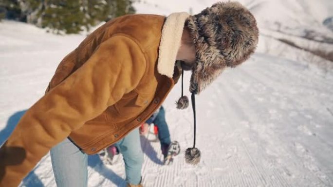 在白雪皑皑的晴天，男友在雪橇上拉着女友上山