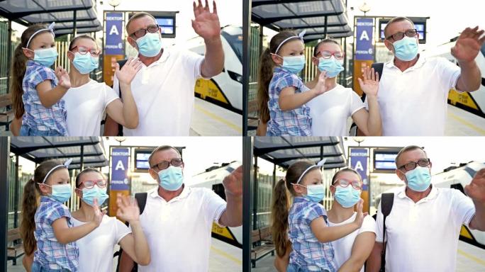 三口之家戴着防护口罩，在火车站遇见某人。一个年轻的女人，她的父亲和小女儿高兴地挥舞着双手