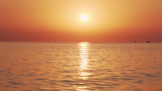 太阳日出背景下有小浪的海面滑动慢动作。太阳升起在海面上，太阳路径在水面上。水面纹理平静