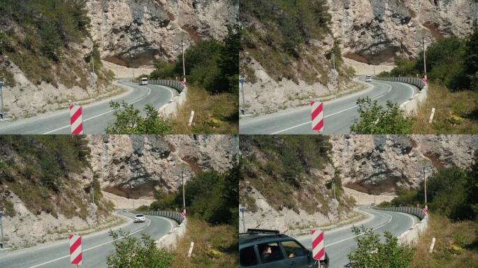 山区有交通标志的弯曲道路。红色对角线保持左障碍物交通标志放置在弯曲的柏油路穿过山区的石头边界上