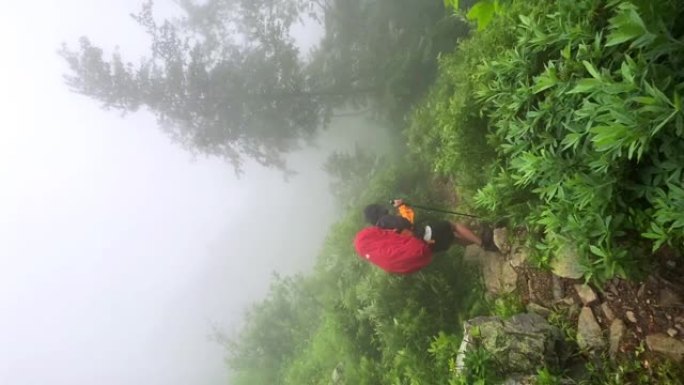 徒步旅行者在迷雾山脉中漫步。阴暗的喜怒无常的天空，强风和大雨。