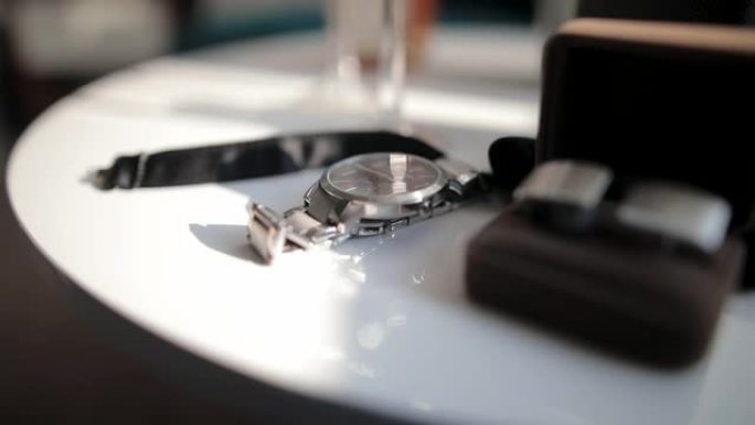 白色圆桌上的手表、袖扣和领结特写