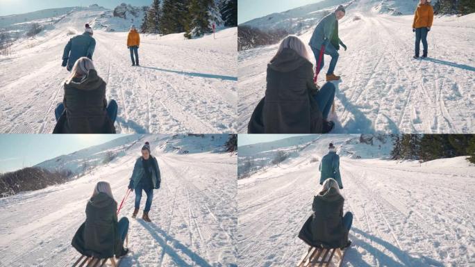 年轻男子拉着一名年轻女子在雪山上的雪橇上