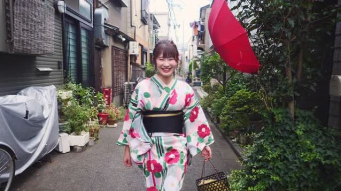 浴衣中的年轻女子走在传统的日本狭窄街道上