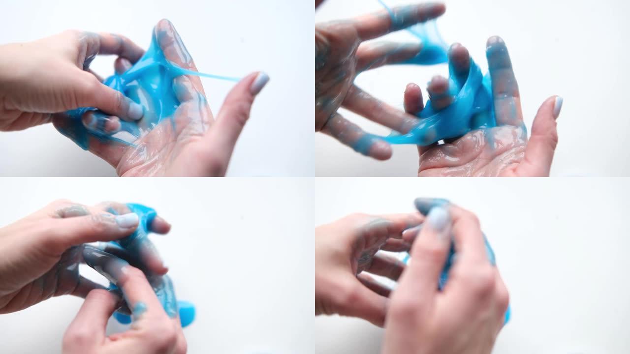 女孩把蓝色粘液伸向两边。玩粘液玩具的女人手。在白色上制作粘液。时髦的液体玩具粘在手上和手指上。4k镜