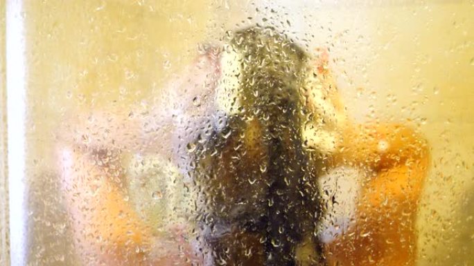 模糊的画面，一个面目全非的女人在洗澡。小女孩站在淋浴间享受着热水滴下来的感觉。美丽的女士照顾自己洗头