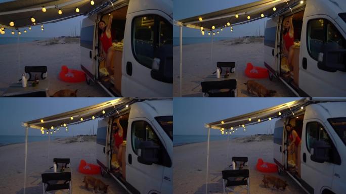 日落时停在海边的露营车附近的女人