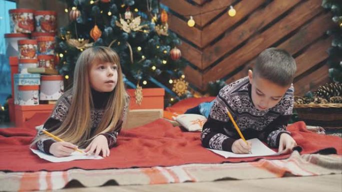 孩子们在冬天的晚上躺在红色毯子上给Nord Pole写信。女孩不知道，这就是她生气的原因。
