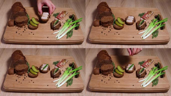 俄罗斯风格的三个三明治: 猪油，鱼，泡菜和葱。白橡木板上的静静。寒冷地区丰盛的食物。