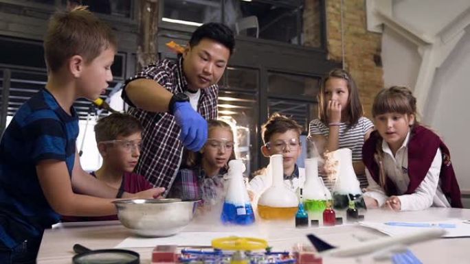 亚洲科学老师为六名学童进行了一项实验，将干冰放入四个装有彩色液体的烧瓶中，用液体烧瓶中的干冰产生了烟