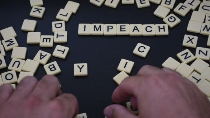 在一个黑色的背景上用两边的混合字母弹劾瓷砖字母。政治、个人或其他美国政府事务的概念。