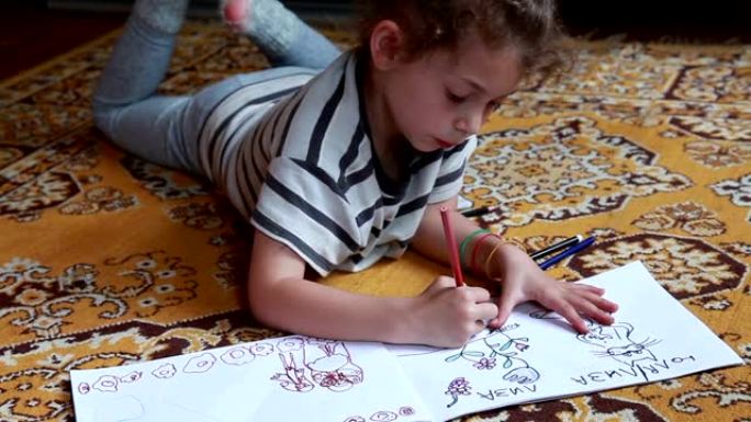 一个小女孩躺在地板上的特写镜头，并在素描本中着色图片