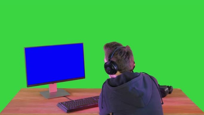 专业玩家在绿屏上看着他的个人电脑，色键