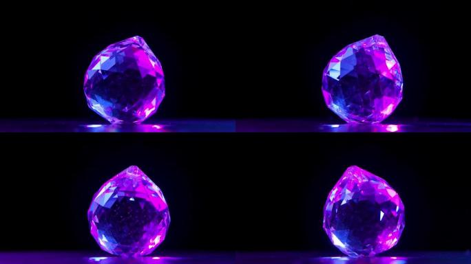 一个大的多面钻石在黑色背景上旋转。石头的刻面在紫罗兰色的光线中闪闪发光，产生眩光。慢动作。特写
