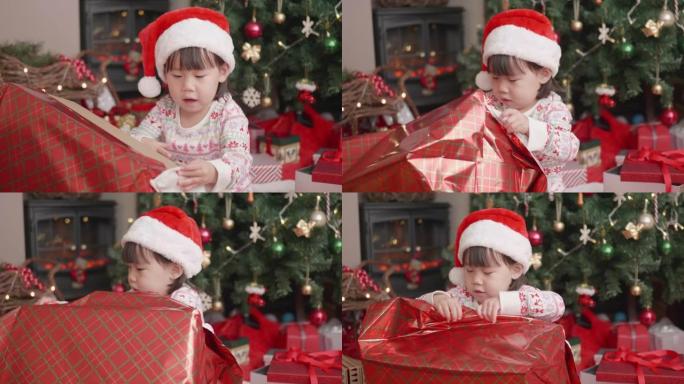 蹒跚学步的女孩在家里的圣诞树旁边打开圣诞礼品盒