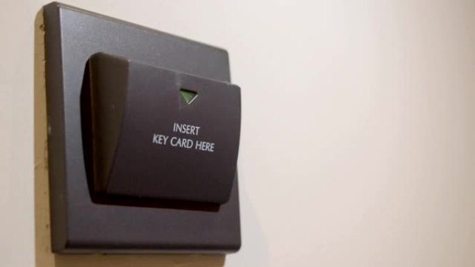 女人将电子智能钥匙卡插入酒店墙上的电源开关支架的特写镜头。