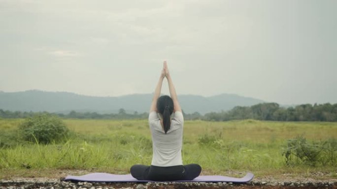 美丽的白人女性坐在冥想中，在美丽的山景中摆姿势瑜伽调息平衡。