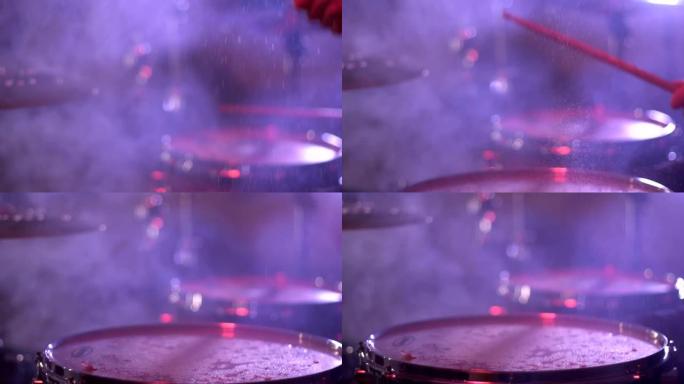 打鼓槌在鼓上滴水，飞溅。在鼓手音乐会上的表演，特写镜头，慢动作