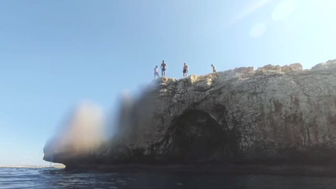 瘦弱的年轻人站在悬崖边上，即将跳入水中，极限运动，恐惧，危险，夏天的乐趣