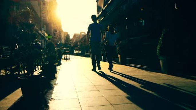 无法辨认的剪影夫妇在欧洲城市的石头路面上的夕阳阳光下行走，快乐旅行的概念，在欧洲度假
