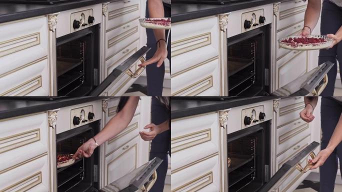 女人把馅饼面团放在烤箱里。放入带有面团的烤箱托盘中，用于覆盆子蛋糕