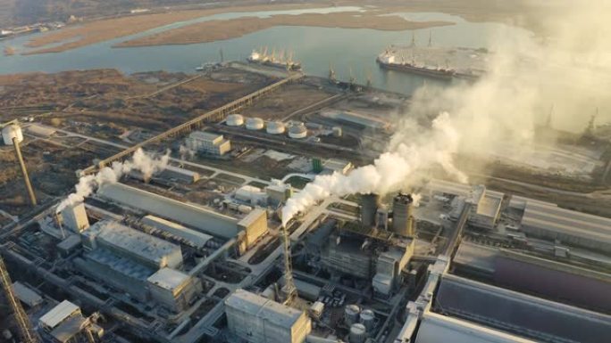 辽阔的大型工业化工厂在冬季日落的明亮灯光下高管鸟瞰图无人机。浓烟来自高高的烟斗。环境污染