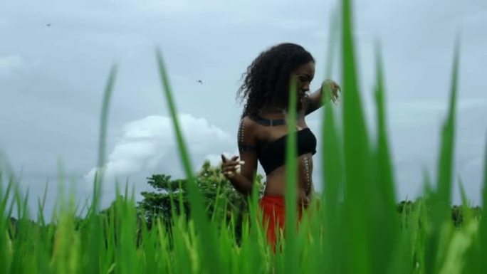 美丽的年轻非洲女孩走在长草的热带花园里