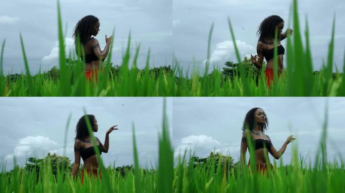 美丽的年轻非洲女孩走在长草的热带花园里