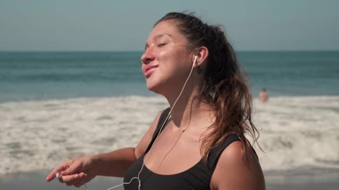 女运动员在海洋的沙质海岸线上听音乐