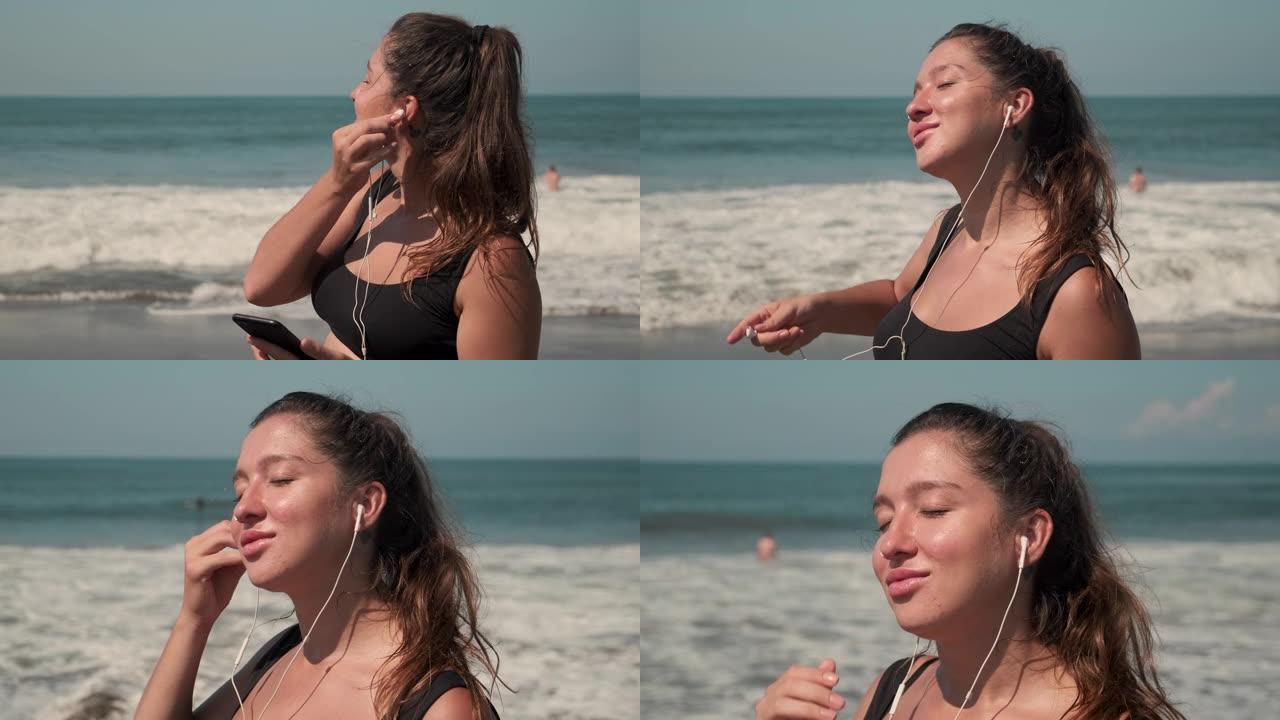 女运动员在海洋的沙质海岸线上听音乐