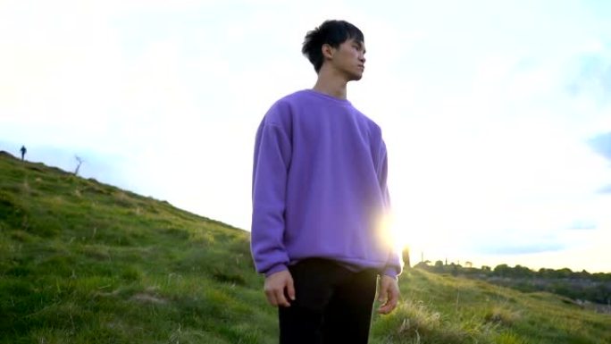 年轻英俊的亚洲男子站在自然环境中与太阳在后面望向远方的肖像