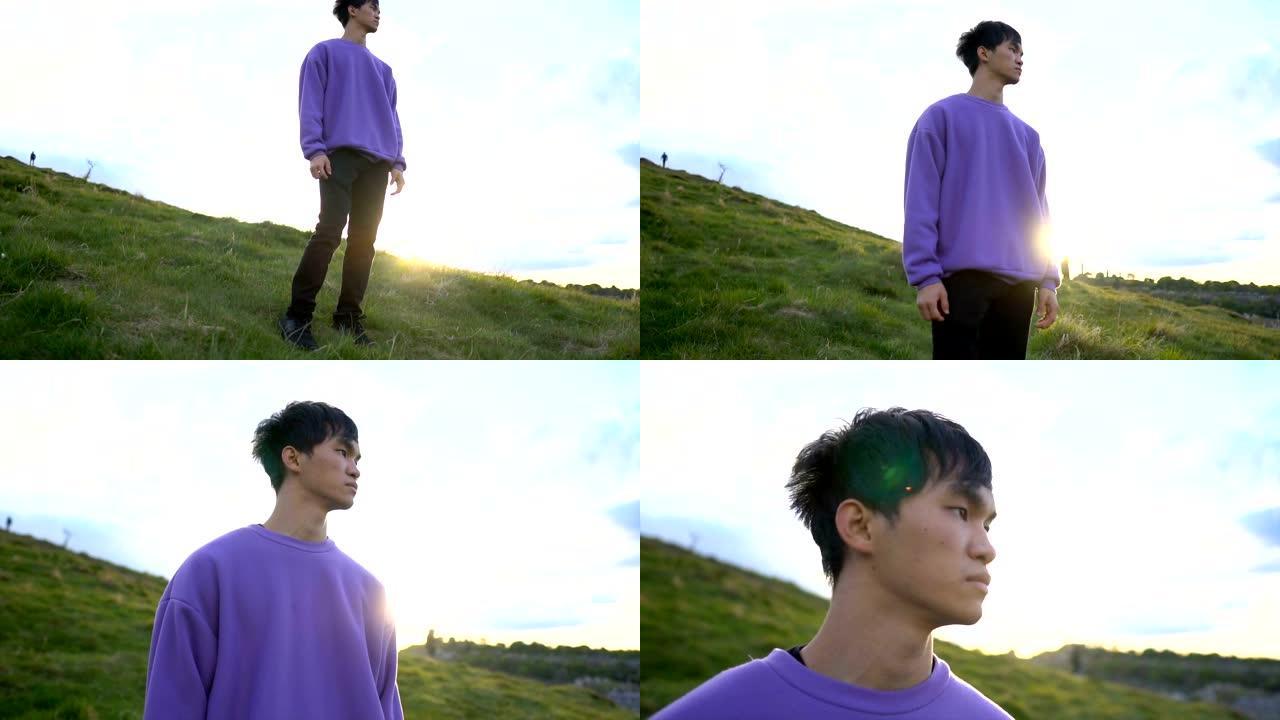 年轻英俊的亚洲男子站在自然环境中与太阳在后面望向远方的肖像