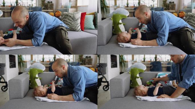 年轻的父亲和他的男婴在沙发上玩耍