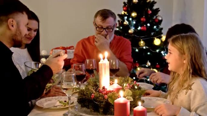 圣诞快乐，圣诞树附近的团结。幸福的家庭正在家里吃饭。人的概念