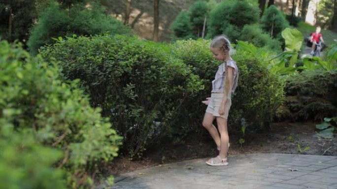 美丽的女孩走过绿色的灌木丛