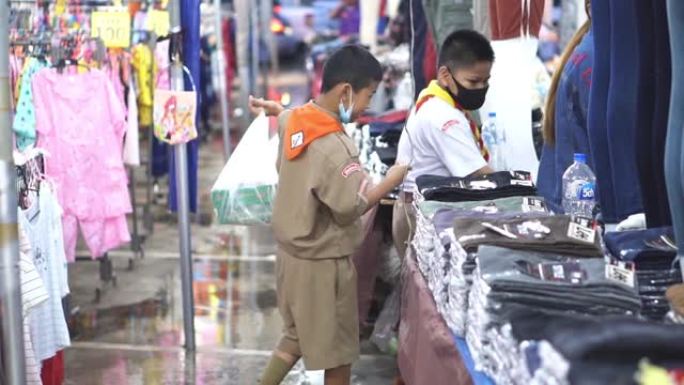 慢动作: 亚洲母婴在市场摊位上买衣服