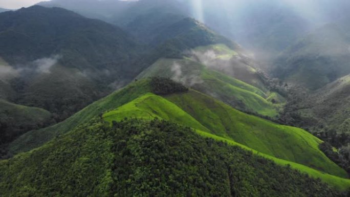 4k空中无人机拍摄，飞向巨大的绿色山顶，高空，大雾，阳光透过云，地球，热带气候，大自然的宝藏，巨大的