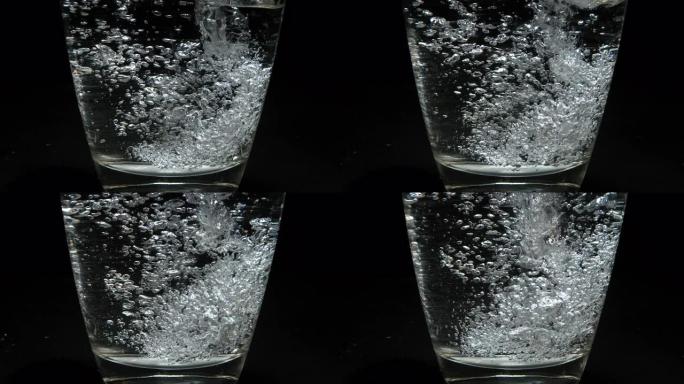 在黑色背景下将水倒入玻璃中，慢动作4K