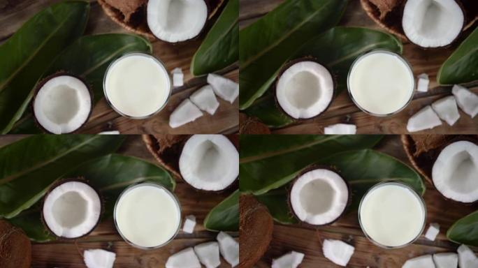 椰奶在玻璃杯和新鲜椰子的一半慢慢旋转。