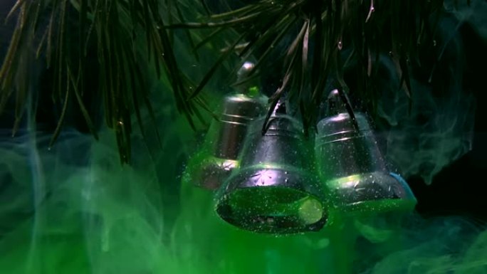 闪亮的银色圣诞铃铛挂在冷杉树枝上。时尚的现代背景。水中的水彩墨水。
