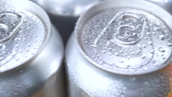 水滴在几罐未标记的汽水，可乐或啤酒上。冰上软饮料的铝苏打锡盖。慢动作极限宏观特写。喝酒止渴。饮料厂。