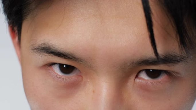 亚洲严肃可爱的人看着相机的眼睛特写。韩国男人面对4k。
