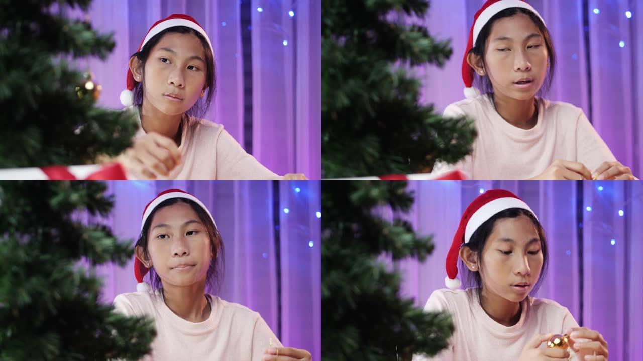 亚洲女孩在家里的圣诞树上悬挂装饰品，准备概念。