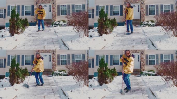 一名身穿黄色夹克的50岁成年长发男子扫过小路，在一场冬季降雪后，将乡间别墅前院的积雪从积雪中扫走。美