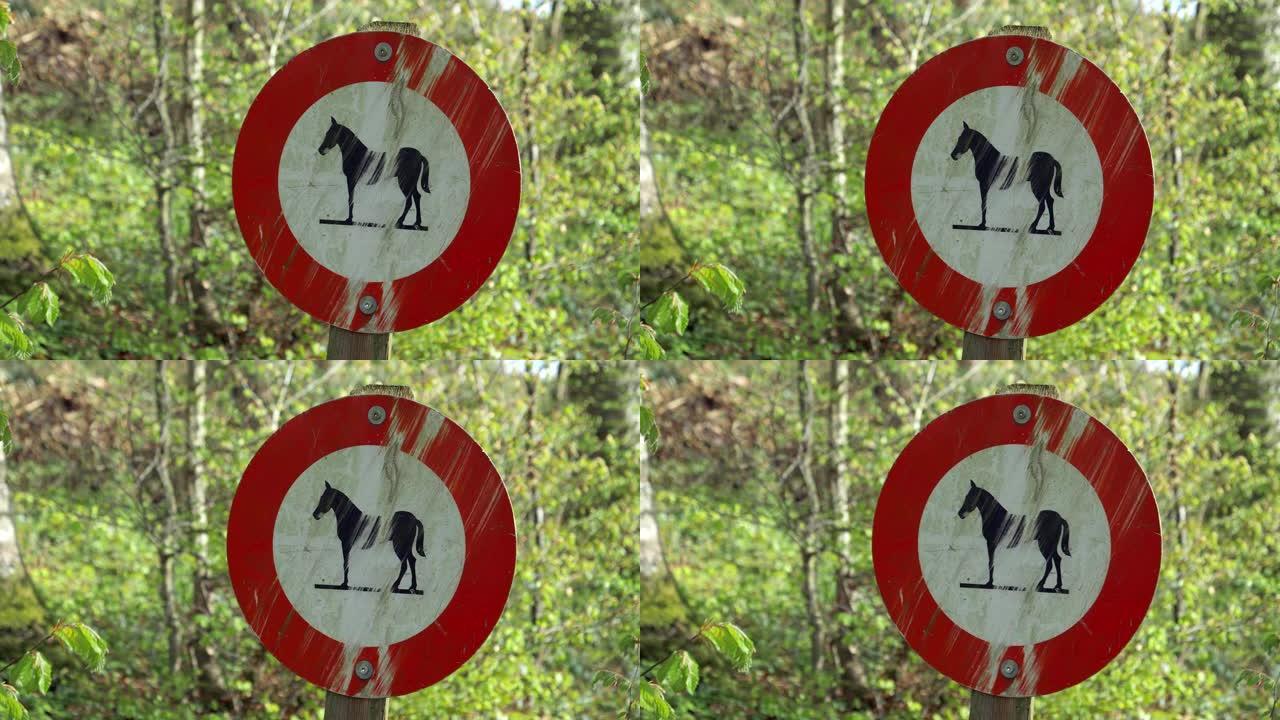 严重弄脏和划伤的禁止马匹标志，背景是一片绿色的森林，白天没有人
