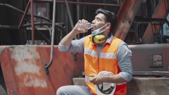 工程师或建筑工人在工作场所喝干净的水并佩戴安全设备，例如安全帽，口罩，耳机，以防止行业发生事故。面罩